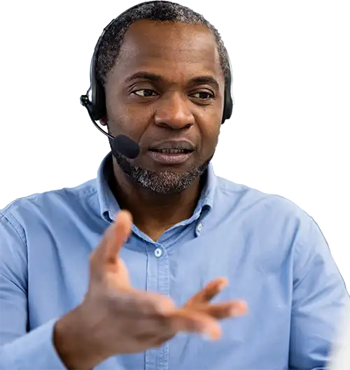 Man wearing a headset and blue shirt gesturing at a screen