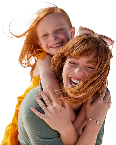 A smiling woman carrying her daughter on her back